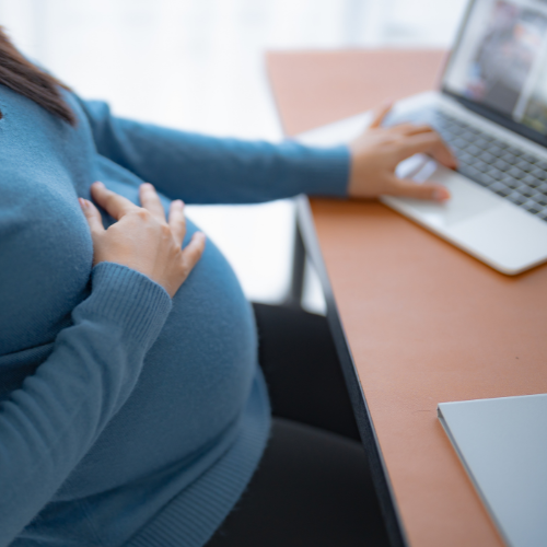 Pregnant employee working on a laptop at her desk, illustrating Allegheny County paid parental leave